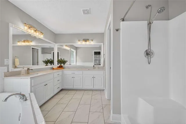 a large white bathroom with a double vanity sink mirror and a bathtub