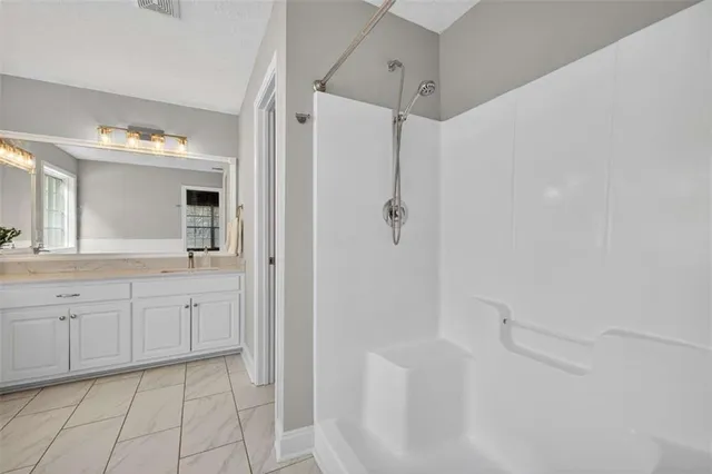 a spacious bathroom with a granite countertop sink mirror and shower