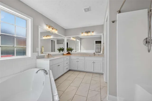a large white bathroom with a large mirror vanity and shower