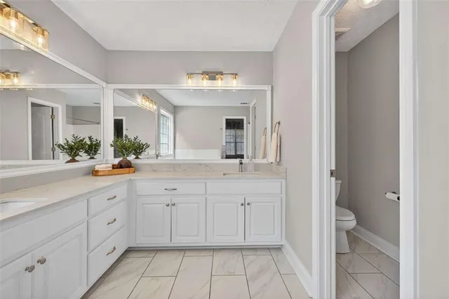 a spacious bathroom with a granite countertop sink a mirror and a toilet