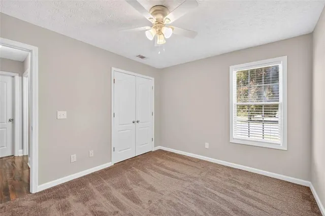 a view of an empty room with a window and a ceiling fan