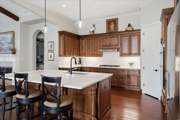 a kitchen with stainless steel appliances granite countertop a kitchen island hardwood floor sink stove dining table and chairs