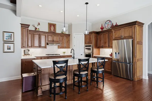 a kitchen with stainless steel appliances granite countertop a table chairs stove and refrigerator