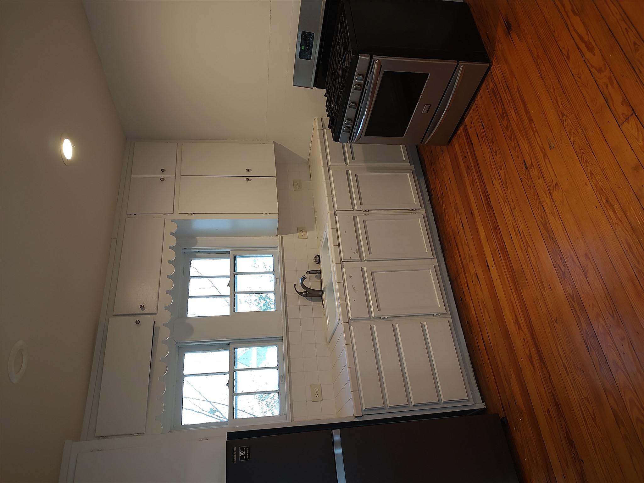 2102 Yellow Jacket Lane, Unit A Austin, TX 78741 - Photo 10 of 15 Kitchen featuring gas stove, freestanding refrigerator, white cabinets, tile counters, and recessed lighting