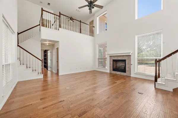a view of an empty room with wooden floor a fireplace and a window