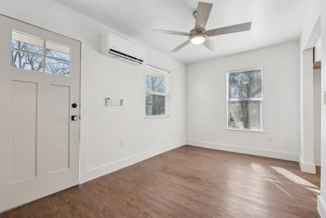 an empty room with wooden floor ceiling fan and windows