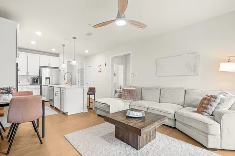 a living room with furniture kitchen view and a chandelier