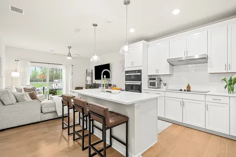 a kitchen with stainless steel appliances kitchen island granite countertop a stove a white table and chairs with white cabinets