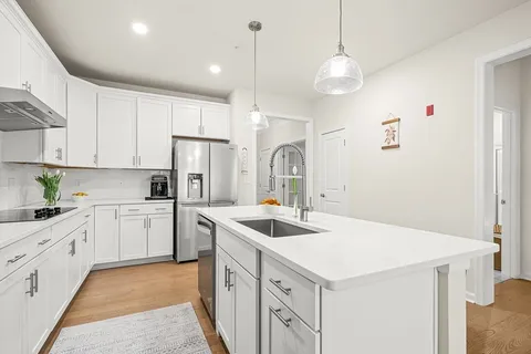 a kitchen that has a lot of white cabinets and stainless steel appliances
