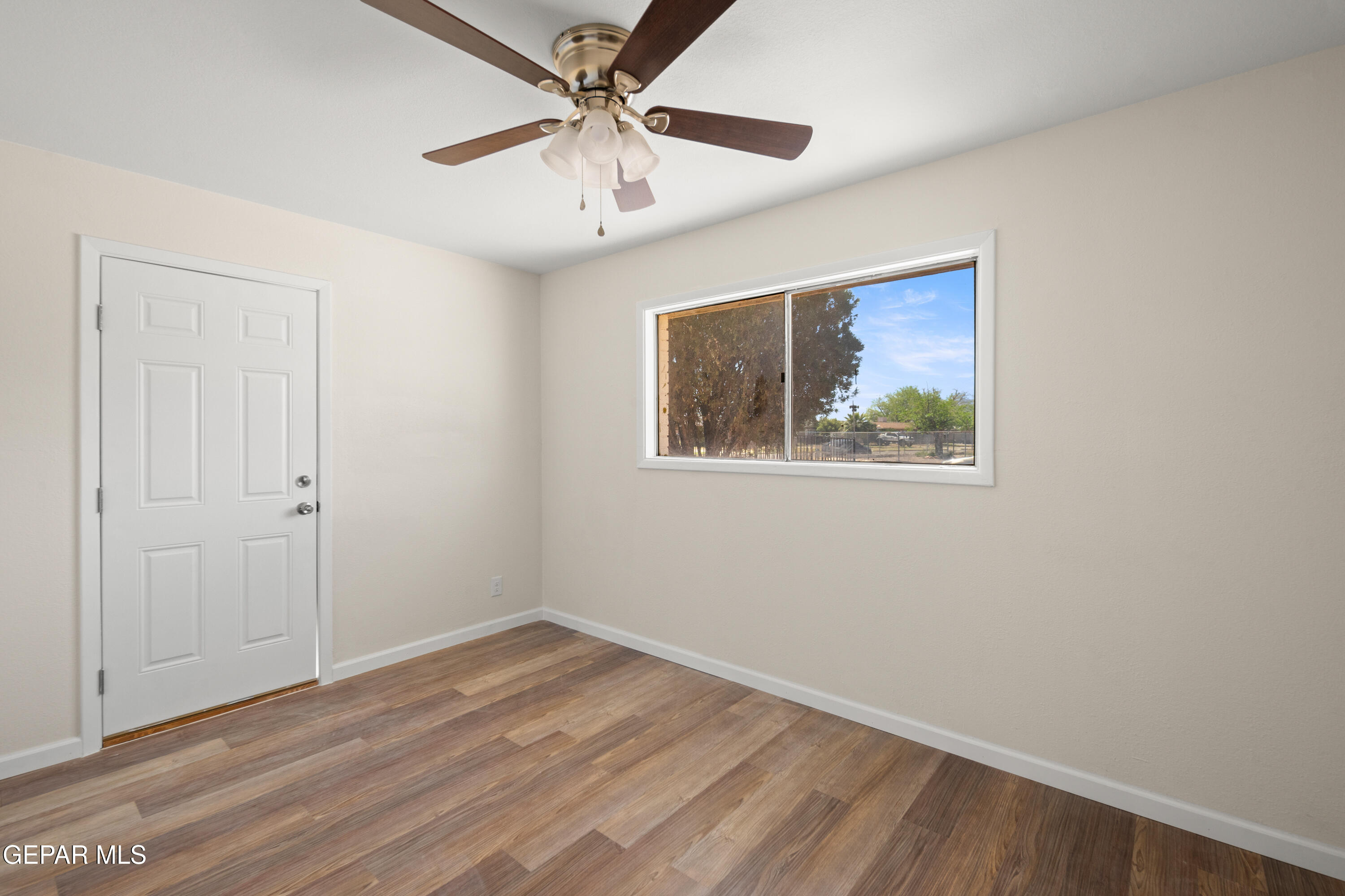 9220 Raleigh Drive El Paso, TX 79924 - Photo 11 of 23 an empty room with wooden floor ceiling fan and windows