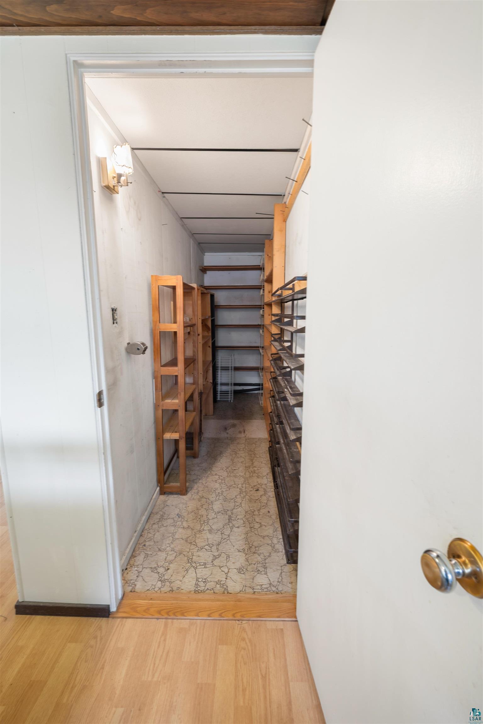 11574 Town Line Road Hibbing, MN 55746 - Photo 19 of 41 Dedicated storage room featuring extensive built-in shelving, durable flooring, overhead lighting, and wood-finish door trim