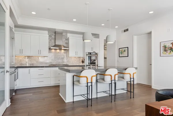 a kitchen with stainless steel appliances kitchen island granite countertop a table chairs sink and cabinets