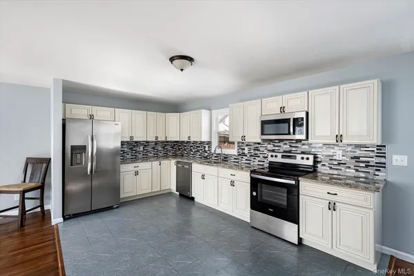 a kitchen with stainless steel appliances granite countertop a stove top oven a sink dishwasher a refrigerator and white cabinets with wooden floor