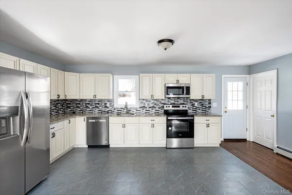 a kitchen with stainless steel appliances granite countertop a stove top oven a refrigerator and white cabinets