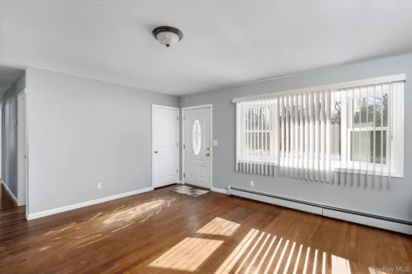a view of an empty room with wooden floor and a window
