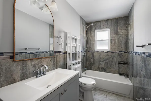 a bathroom with a sink a toilet a mirror and bathtub