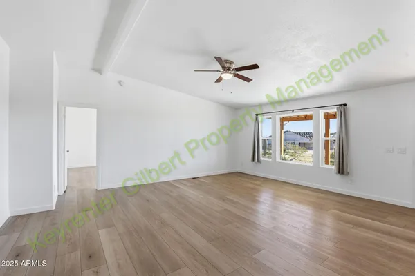 a view of an empty room with a window and wooden floor
