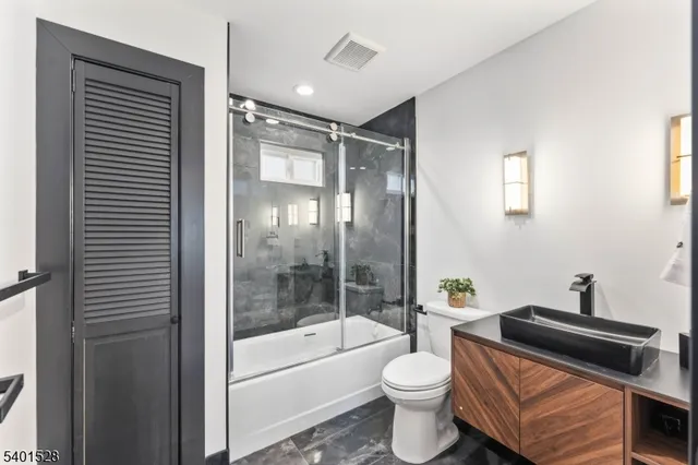 a bathroom with a bathtub shower sink vanity and toilet