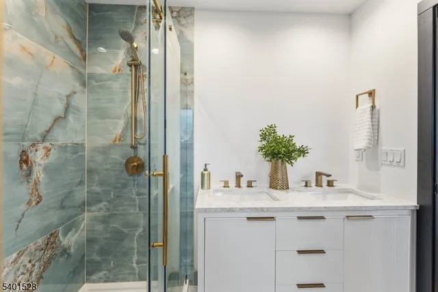 a bathroom with a granite countertop sink a mirror and shower