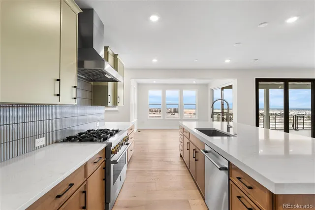 a large kitchen with stainless steel appliances a large counter top a stove and a sink