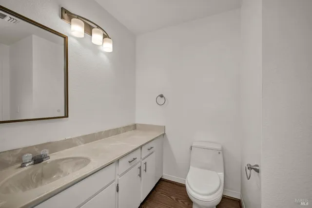 a bathroom with a granite countertop sink mirror vanity and toilet