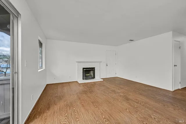 a view of empty room with wooden floor and fireplace