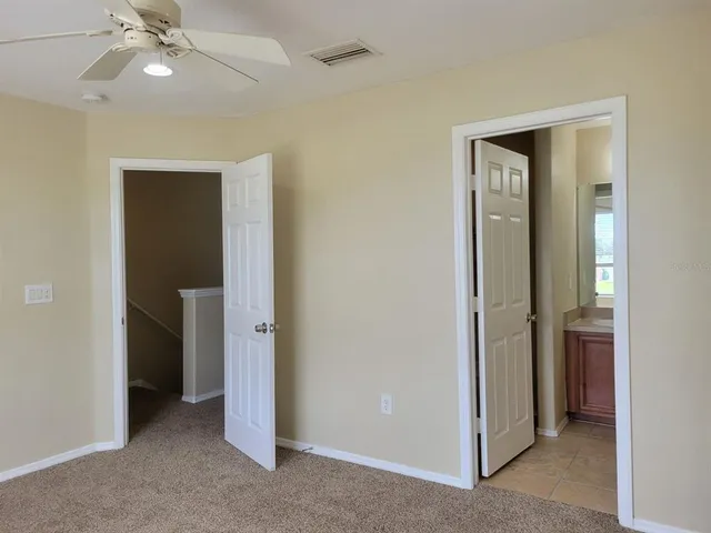 an empty room with a ceiling fan and a bathroom