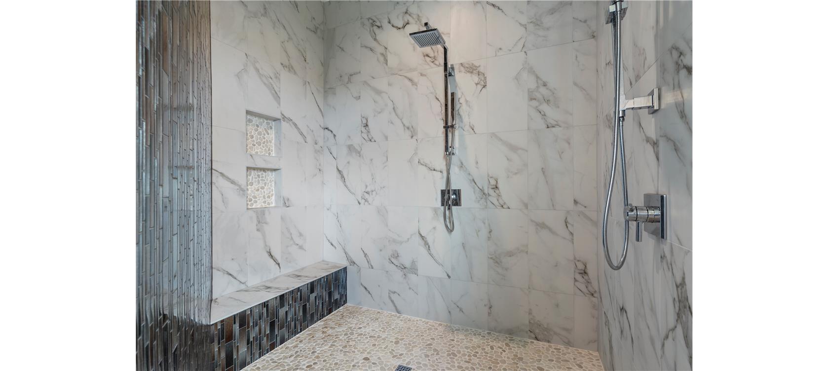 1805 Performer Road Spicewood, TX 78669 - Photo 13 of 40 oversized walk-in shower featuring gorgeous marbled tile walls, a built-in bench with mosaic tile accents, two recessed shower heads and niches.