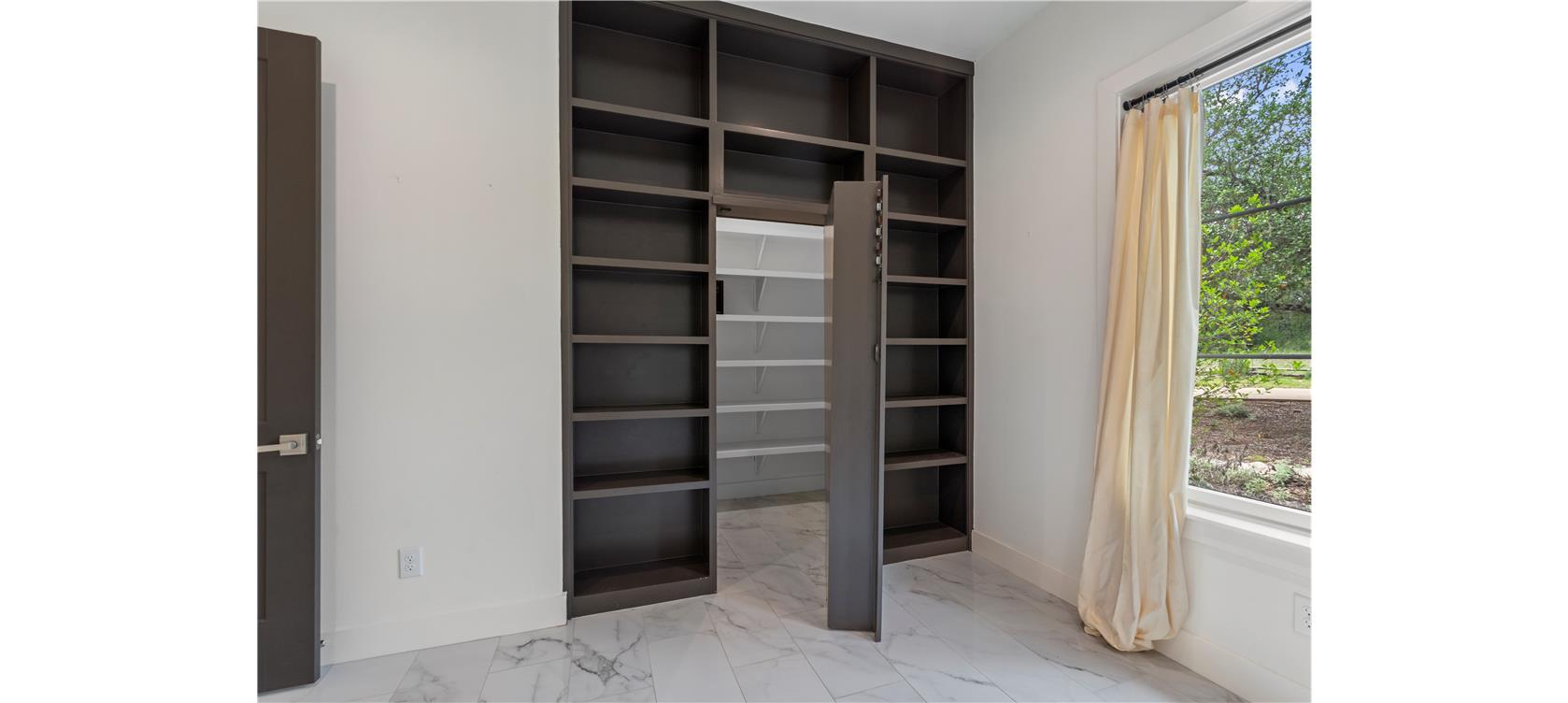 1805 Performer Road Spicewood, TX 78669 - Photo 17 of 40 private office featuring custom built in bookshelves with a hidden access door leading to additional storage space- perfect for organization and functionality