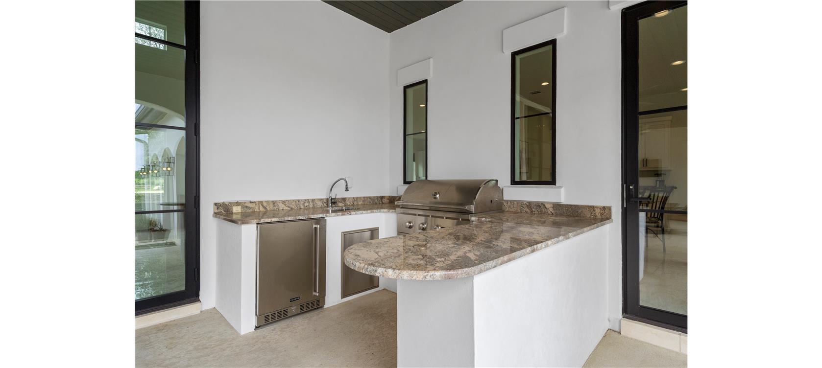 1805 Performer Road Spicewood, TX 78669 - Photo 23 of 40 Outdoor kitchen featuring a built-in grill, and sink, and a stainless steel undercounter refrigerator right off the kitchen