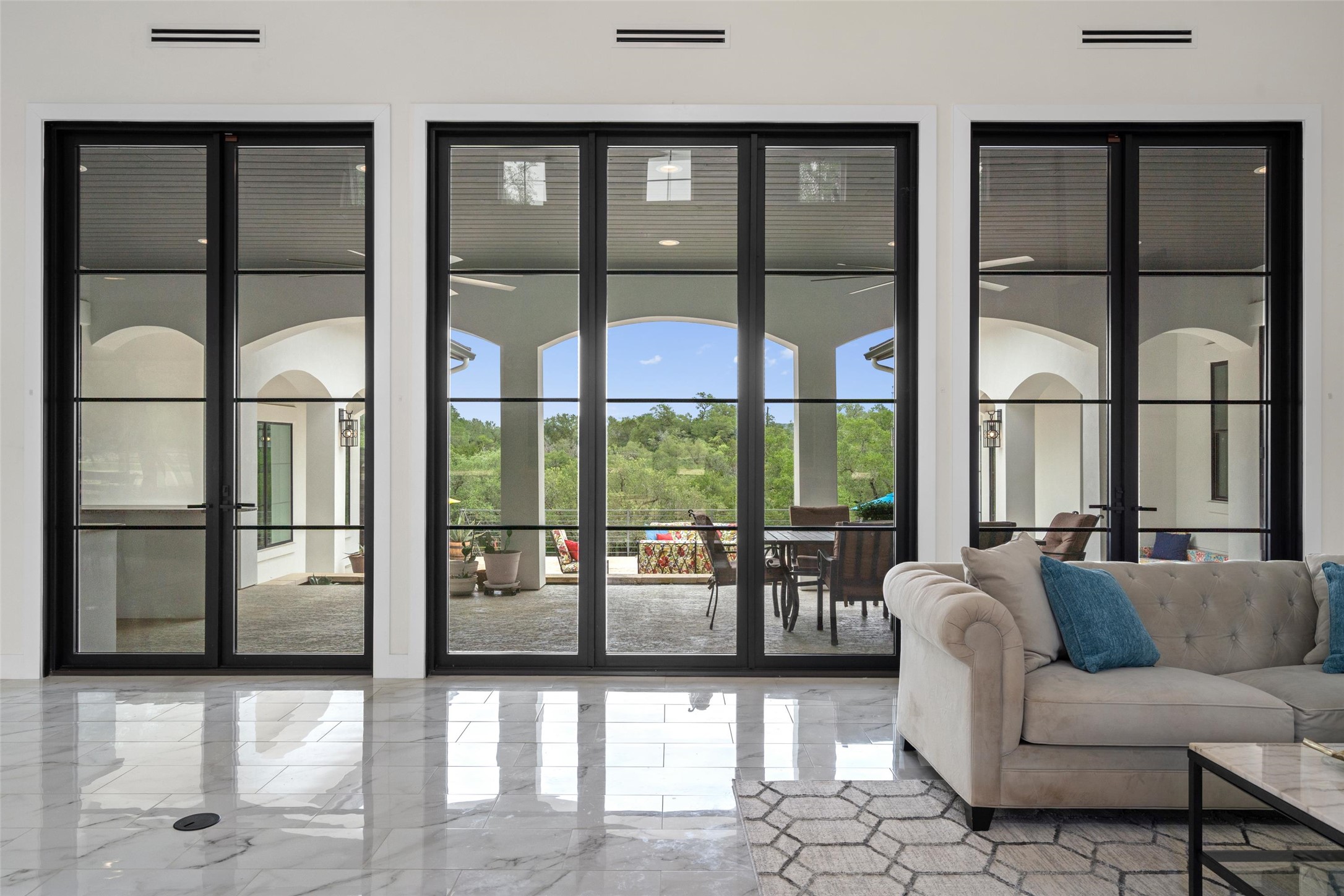 1805 Performer Road Spicewood, TX 78669 - Photo 5 of 40 Expansive black-framed sliding glass doors fill the space with natural light and open to a covered patio with serene country views