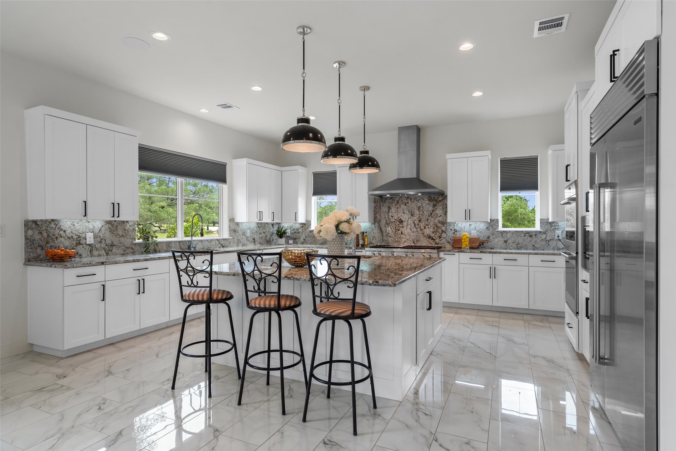 1805 Performer Road Spicewood, TX 78669 - Photo 7 of 40 Chef inspired kitchen featuring a large kitchen island, white cabinetry, integrated stainless steel appliances, and stylish finishes-perfect for cooking, gathering, and entertaining.
