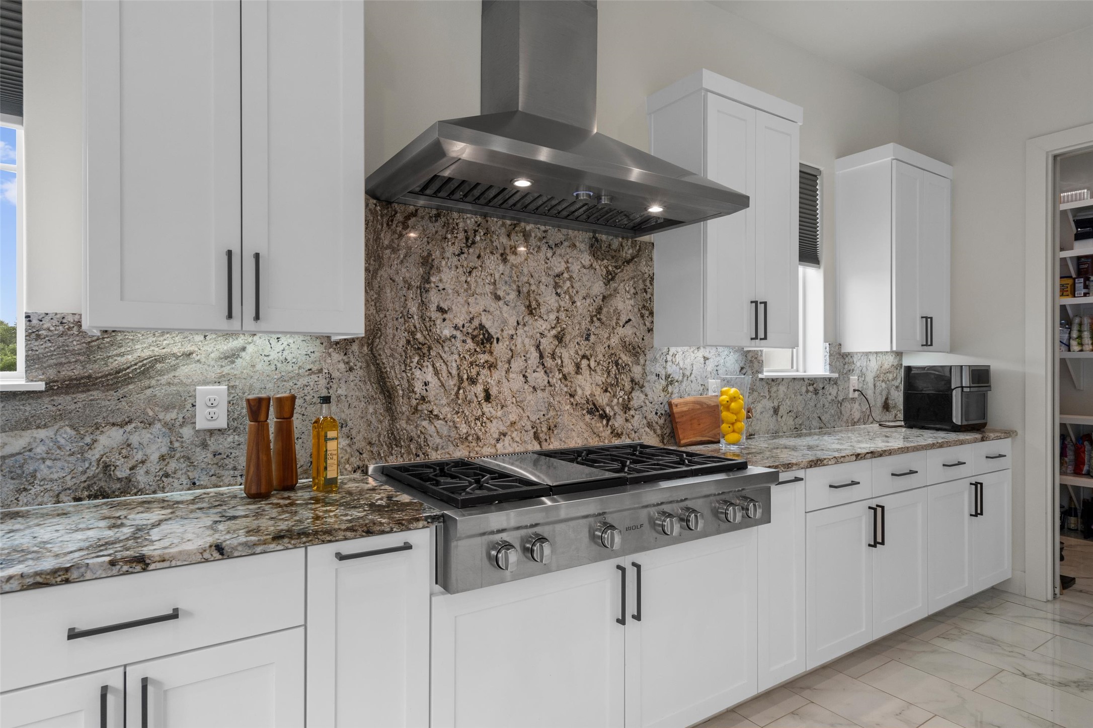 1805 Performer Road Spicewood, TX 78669 - Photo 9 of 40 Gourmet kitchen featuring a stainless-steel gas range with a matching range hood complete this chefs kitchen