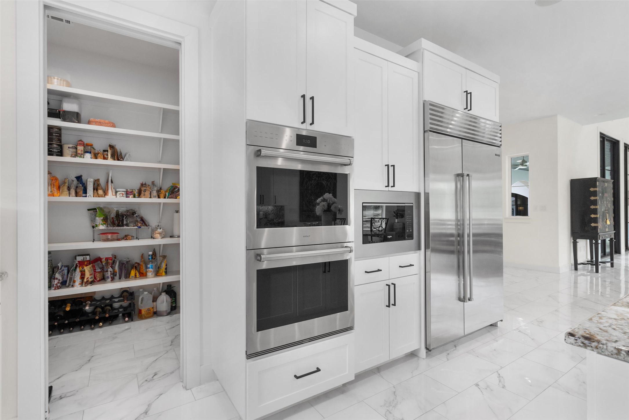 1805 Performer Road Spicewood, TX 78669 - Photo 9 of 40 Modern kitchen featuring white cabinetry, stainless steel double ovens, a built-in microwave, a side-by-side refrigerator, and a huge walk-in pantry