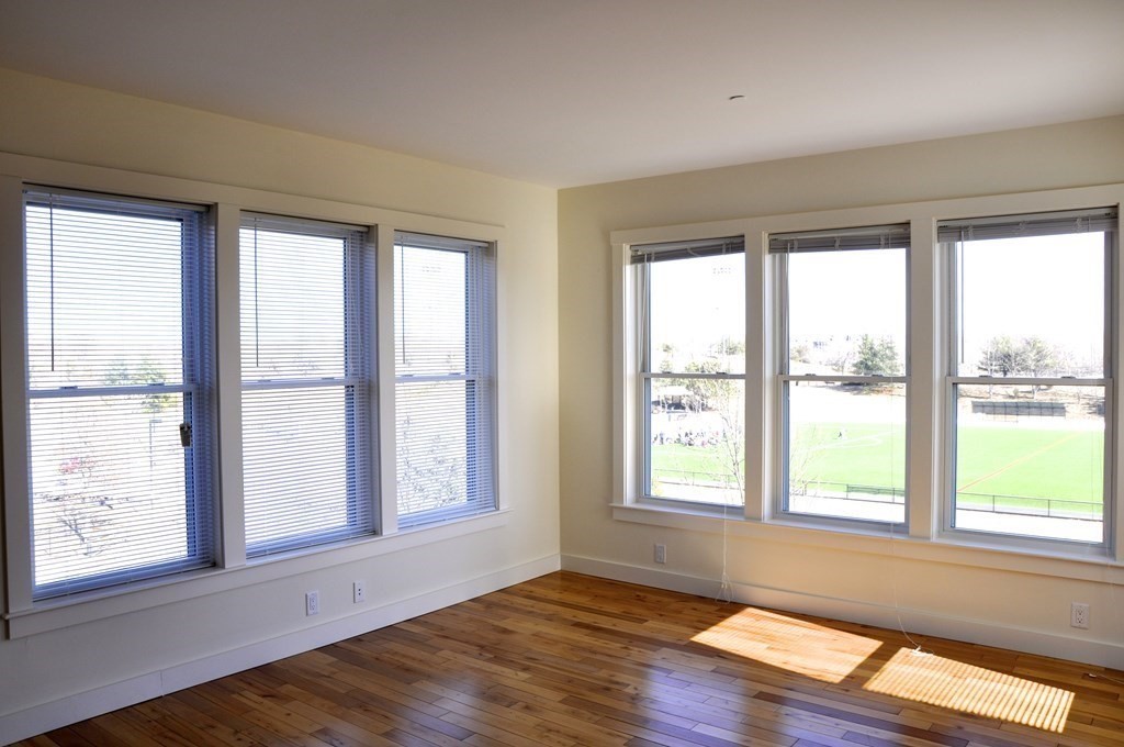 87 New Street, Unit 314 Cambridge, MA 02138 - Photo 4 of 12 a view of an empty room with wooden floor and a window