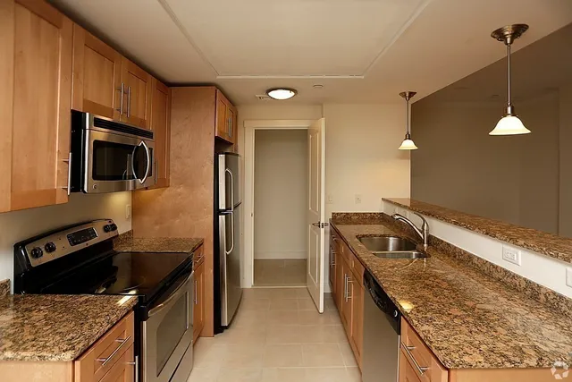 a kitchen that has a sink wooden cabinets and stainless steel appliances