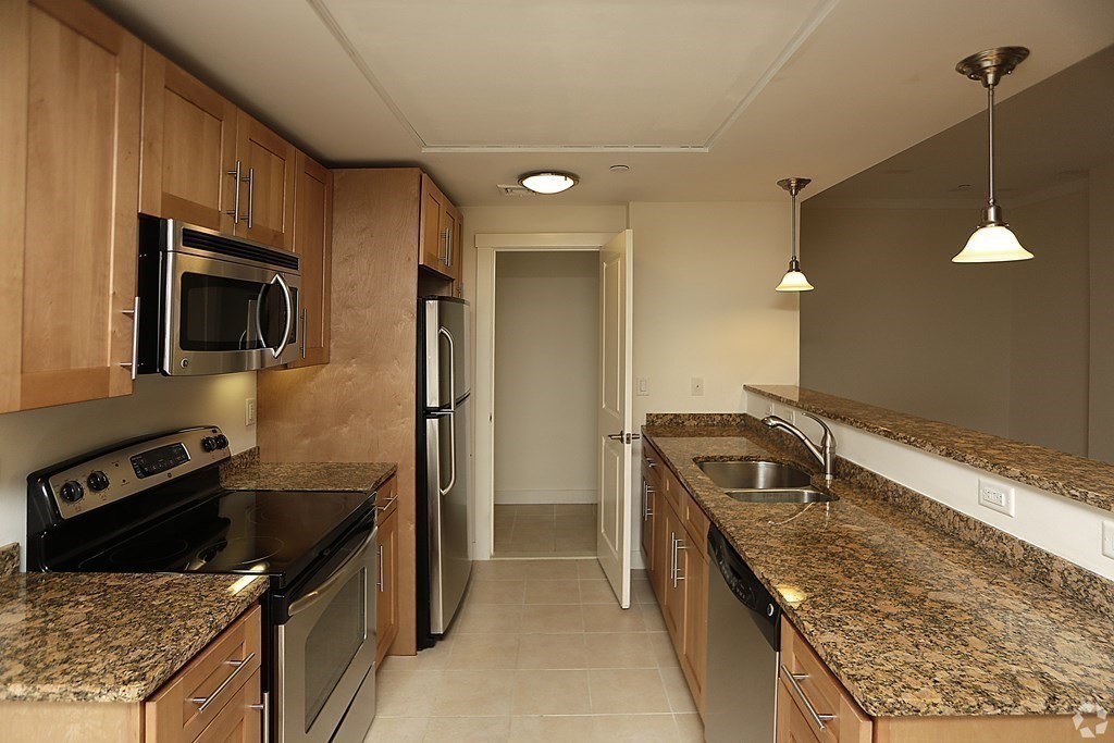 87 New Street, Unit 314 Cambridge, MA 02138 - Photo 6 of 12 a kitchen that has a sink wooden cabinets and stainless steel appliances