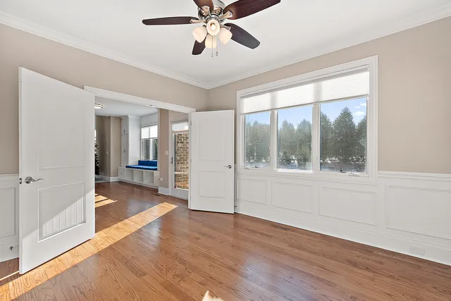 an empty room with chandelier fan and windows