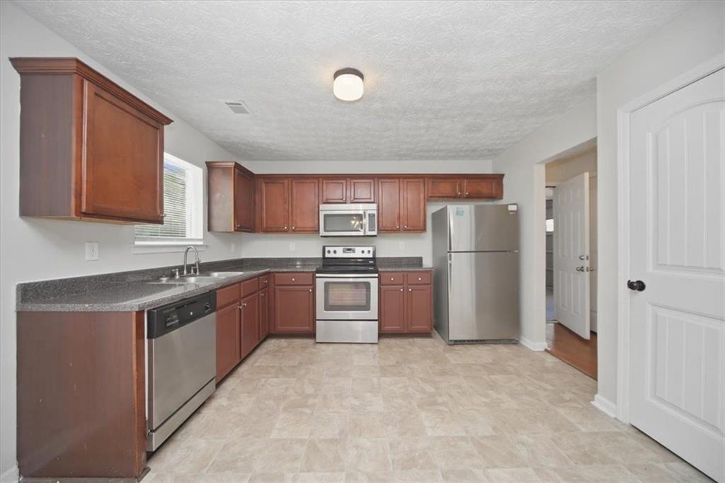 100 Wexford Way Covington, GA 30014 - Photo 13 of 37 a kitchen with stainless steel appliances granite countertop a refrigerator and a stove top oven