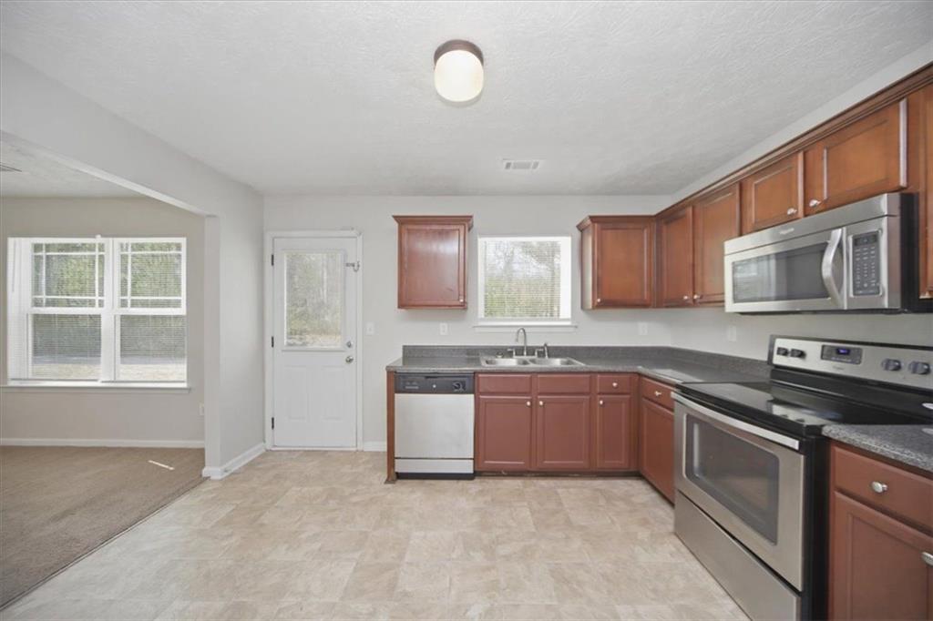 100 Wexford Way Covington, GA 30014 - Photo 14 of 37 a kitchen with stainless steel appliances granite countertop a stove sink and cabinets