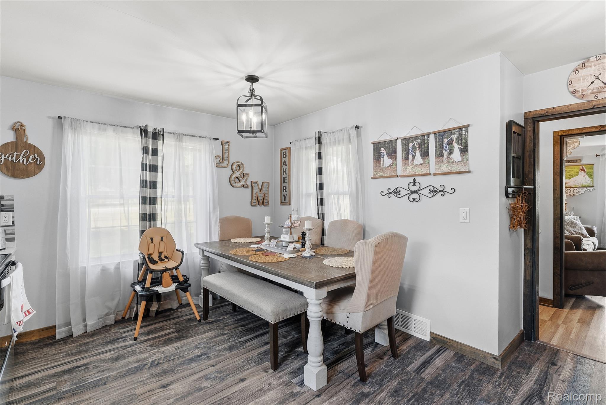 8403 Miller Road Swartz Creek, MI 48473 - Photo 18 of 37 Dining area featuring wood-finish flooring, white walls, and a prominent dark bronze lantern-style light fixture