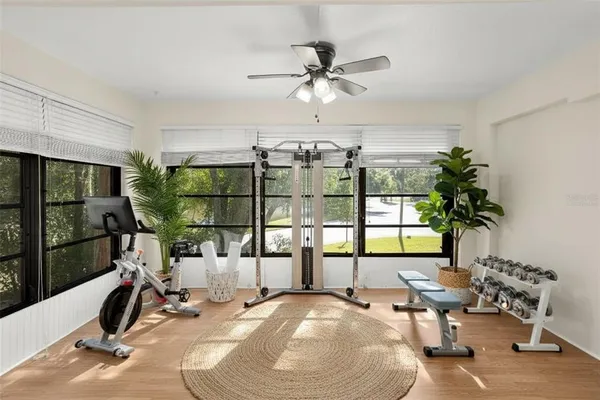 an empty room with wooden floor fan and windows