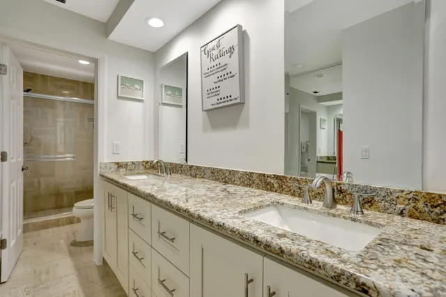 a bathroom with a granite countertop double vanity sink and a mirror