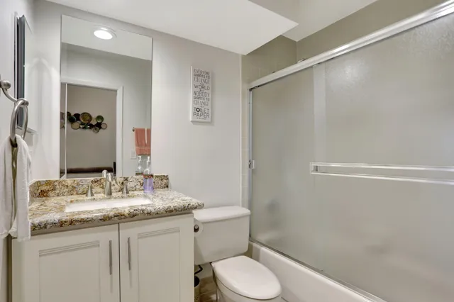 a bathroom with a granite countertop sink toilet and shower
