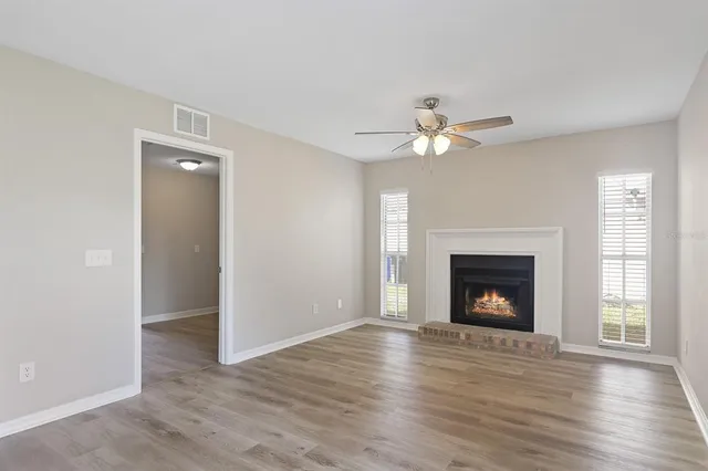 a view of an empty room with wooden floor fireplace and a window