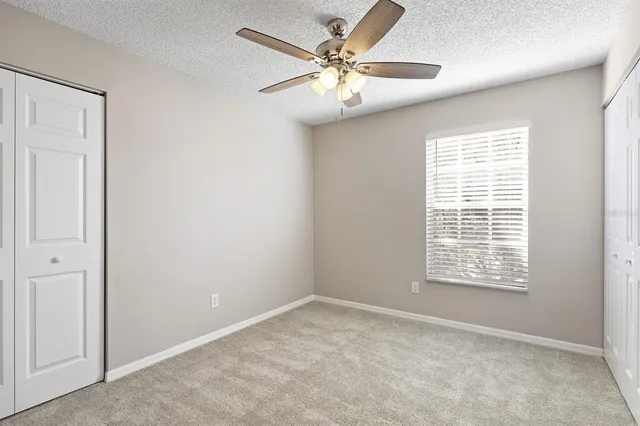 an empty room with windows and fan