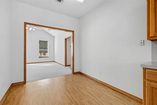 a view of a hallway with wooden floor and a bathroom