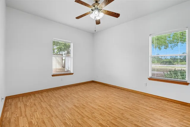 a view of an empty room with a window and wooden floor