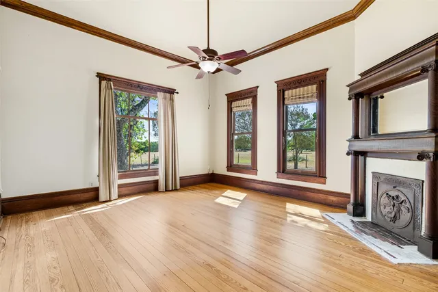 a view of a livingroom with a fireplace a ceiling fan and wooden floor