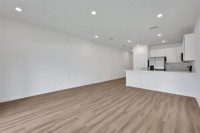 a view of a kitchen with kitchen island wooden floor center island and stainless steel appliances